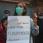 Protesterande kvinna håller ett plakat med texten ”Girls just wanna have fundamental human rights”