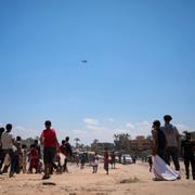 Palestinier väntar på flygplan som ska släppa ner nödhjälp.