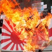 Sydkoreanska demonstranter bränner en bild på Japans premiärminister samt flaggan som användes av japanska imperiet under andra världskriget. Flaggan återupptogs senare av Japans flotta. 