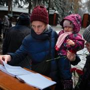 En kvinna håller sitt barn vid en minnesplats i Moskva. Arkivbild från 2023.