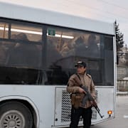 Syriska säkerhetsstyrkor utanför bussar som uppges transporterar SDF-medlemmar som överlämnat sig på lördagen.