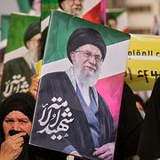 En kvinna håller upp en bild på den tidigare ayatollan Ali Khamenei.
