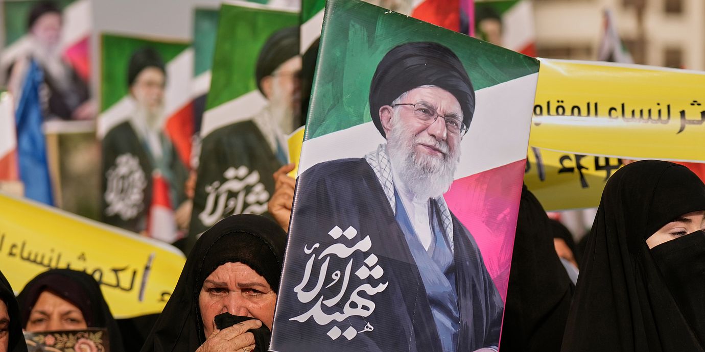 En kvinna håller upp en bild på den tidigare ayatollan Ali Khamenei.