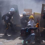 Demonstranter skyddar sig med sköldar mot militären i Myanmar.