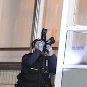 En polis fotograferar ett kulhål i en inglasad balkong där ett skott gått in efter dödsskjutningen på Docentgatan.