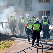 Kravallutrustad polis tar sig förbi en barikad vid Ringdansen centrum under upploppen i Navestad i Norrköping på påskdagen 2021.