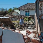 En man tittar på ett hus som har rasat på Lombok. 