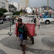 Vendor Andre Luiz hauls his beach chairs from Copacabana Beach amid the new coronavirus pandemic in Rio de Janeiro, Brazil, Friday, March 5, 2021. New measures took effect on Friday, aiming to halt the spread of COVID-19.
