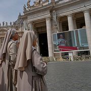 Människor ser påve Leo XIV tala i Vatikanstaten på söndagen.