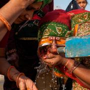 Kvinnor dricker vatten nära floden Ganges i Sangam, Indien.