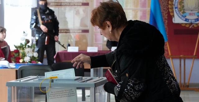 En vakt övervakar röstningen i en vallokal i Luhansk. AP
