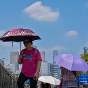 Folk i Kinas huvudstad Peking försöker skymma sig mot solen.