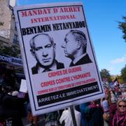 Demonstrant i Paris håller upp ett plakat som påminner om att Netanyahu är internationellt efterlyst för krigsbrott.