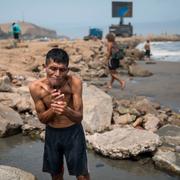 Pio Isidro Morales, 59, rakar och tvättar sig med havsvatten på stranden i Lima därför att han saknar vatten hemma. 15 mars 2020.