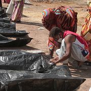 Anhöriga kontrollerar namnlappar på liksäckar vid en gravplats i Khartum i Sudan.