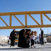 En palestinsk kvinna passerar under en avspärrning vid Hebron.