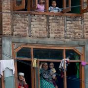 Människor blickar ut över en ceremoni i Indien-kontrollerade områden i Kashmir. 