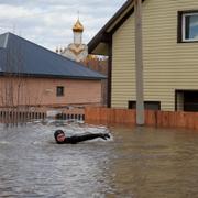 En invånare i ryska Orenburg simmar över en översvämmad gata. 