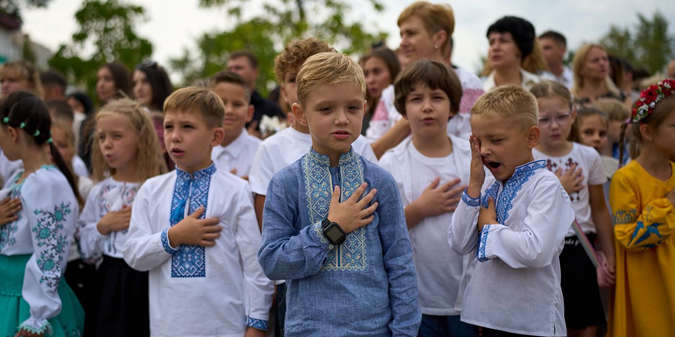Drygt 20 000 ukrainska barn ska ha förts till Ryssland eller ryskkontrollerat område sedan 2014. På bilden syns barn och föräldrar som sjunger Ukrainas nationalsång under skolstartsfiranden i Kyjiv, den 1 september 2026.