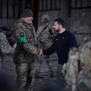 Zelenskyj skakar hand med en soldat våren 2023.