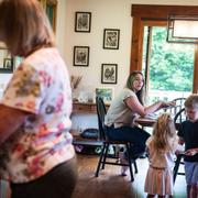 Carmen Haslam works from her kitchen, where her children sometimes join her calls. Her mother, Camille Daigle, left, takes care of the kids three days a week.