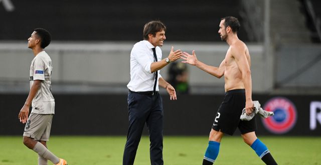 Inters huvudtränare Antonio Conte ler mot spelaren Diego Godin.  Sascha Steinbach / TT NYHETSBYRÅN