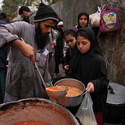 Palestinsk flicka tar emot mat i Deir al-Balah i juli 2026.