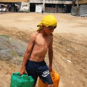 En pojke bär dunkar med vatten i Gaza City.  