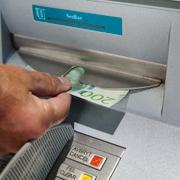 En person tar ut pengar ur en bankomat. Arkivbild. 