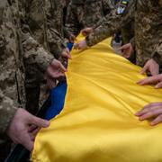 Arkivbild: Soldater draperar en ukrainsk flagga över sin döde kamrats kista.