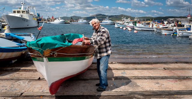 En äldre man pysslar om sin båt på den italienska ön Sardinien – en av världens fem blå zoner. Shutterstock