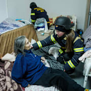 Ett räddningsteam undsätter en äldre kvinna efter en rysk attack.