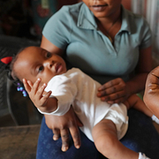 Till vänster: Ett spädbarn i Nigeria vaccineras mot malaria i  december 2024. Till höger: Sveriges socialminister Jakob Forssmed (KD) under en pressträff i början av juli i år.