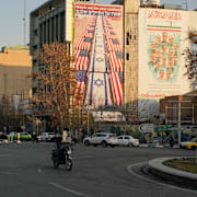 Mopeder kör förbi anti-amerikanska och anti-israeliska affischer i Irans huvudstad Tehran.
