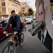 En cyklist passerar en skylt där Bashar al-Assads ansikte förstärkts med en sko.