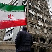 En man håller den iranska flaggan vid ett sjukhus i Teheran som skadats i attackerna i helgen.