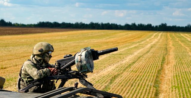 Rysk soldat bevakar skörden på ett fält i Ukraina.  AP