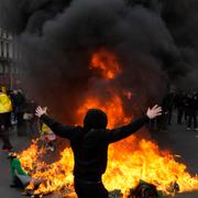 En svartklädd demonstrant gestikulerar framför en soptunna som satts i brand under en demonstration mot landets pensionsreform som hölls i Paris, den 28 mars, 2023.