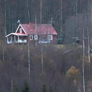 Rött hus bland hösgula träd i Lekvattnet i Värmland.