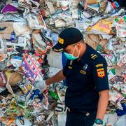 En tulltjänsteman inspekterar en container med avfall. 