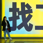 Kvinna framför skylt med texten ”söker jobb” i Beijing.