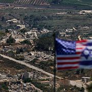 Israeliska och amerikanska flaggor framför förstörda byggnader i södra Libanon.