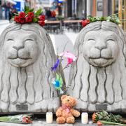 Blommor och ljus vid två Stockholmslejon på Drottninggatan. 