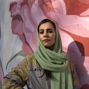 Women’s-rights activist Marjan Amiri stands beside a mural in Kabul depicting Farkhunda Malikzada, who was killed by a mob in the capital in 2015.