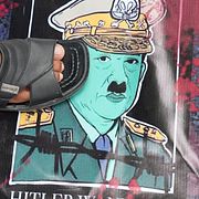 En myanmarier boende i Thailand trampar på en poster där president Min Aung Hlaing framställts som Hitler under en protest i Bangkok i dag.