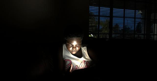 En ung flicka använder solenergi för att ladda sin telefon. Tsvangirayi Mukwazhi / TT NYHETSBYRÅN
