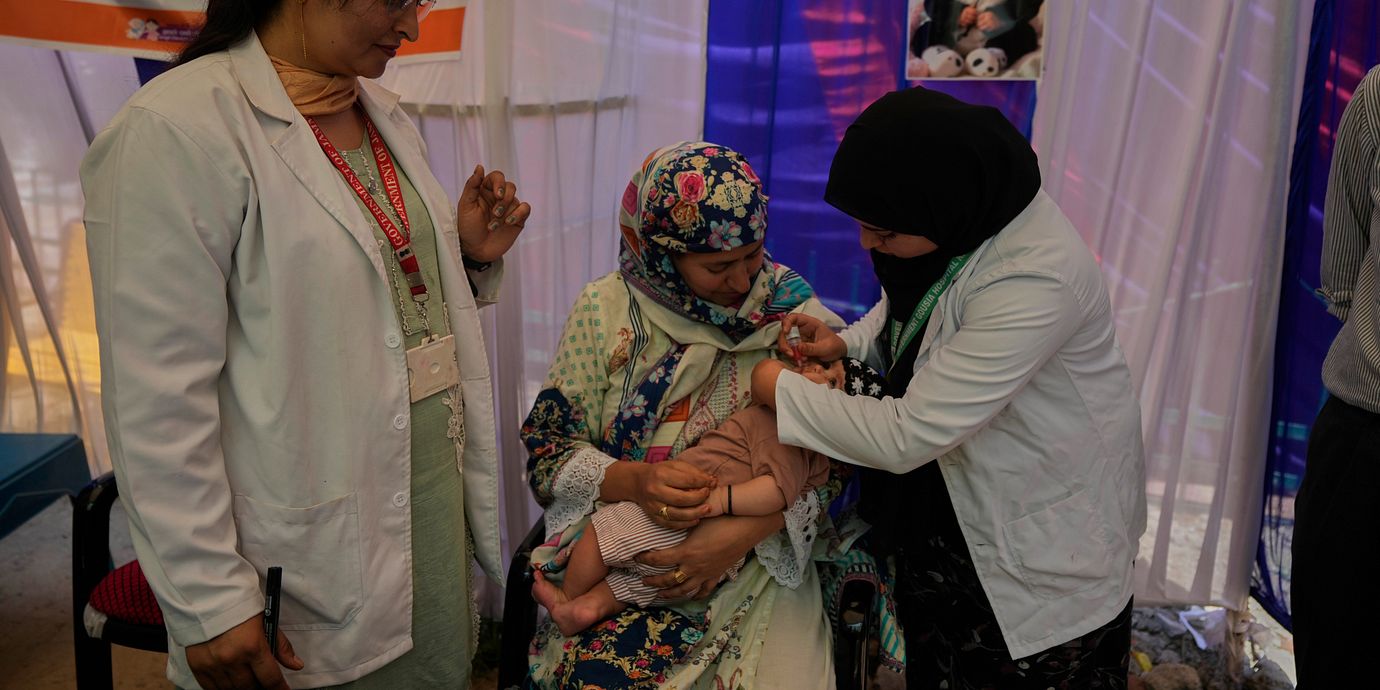 En sjukvårdare ger poliovaccin till ett litet barn i Kashmir. Bild från 28 juni.