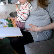 Gravid kvinna läser en bok för sitt barn.