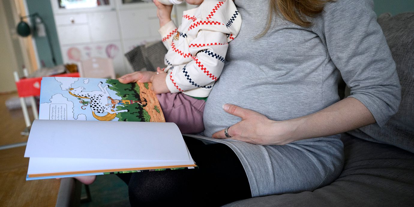 Gravid kvinna läser en bok för sitt barn.