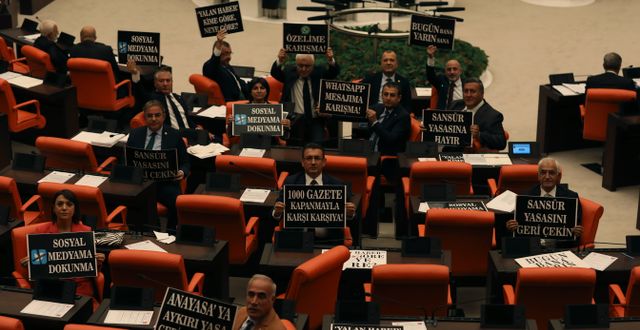 Oppositionspolitiker håller upp kritiska skyltar i parlamentet Burhan Ozbilici / AP